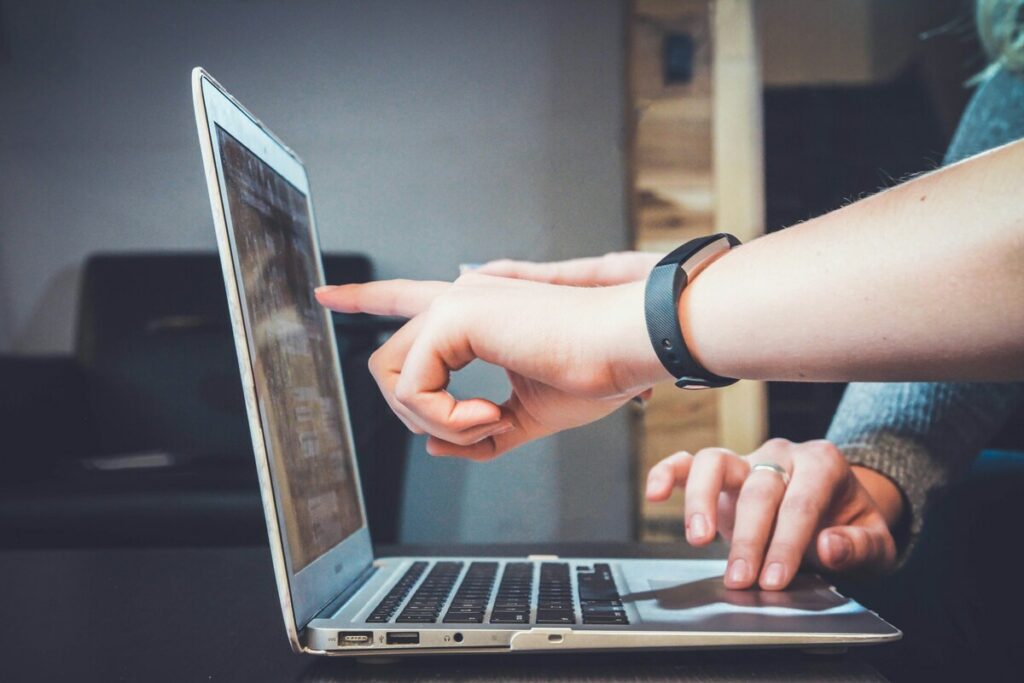 A person pointing on a laptop screen