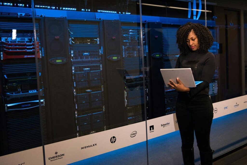 A woman using a laptop beside a data server