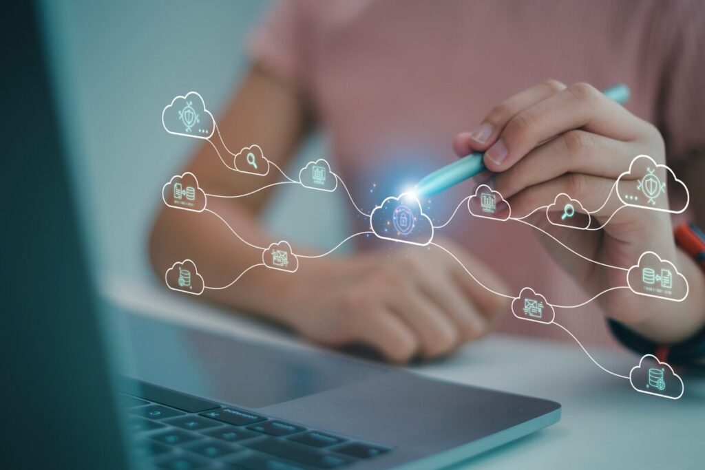 A woman using a laptop and pointing to cloud icons with a pen
