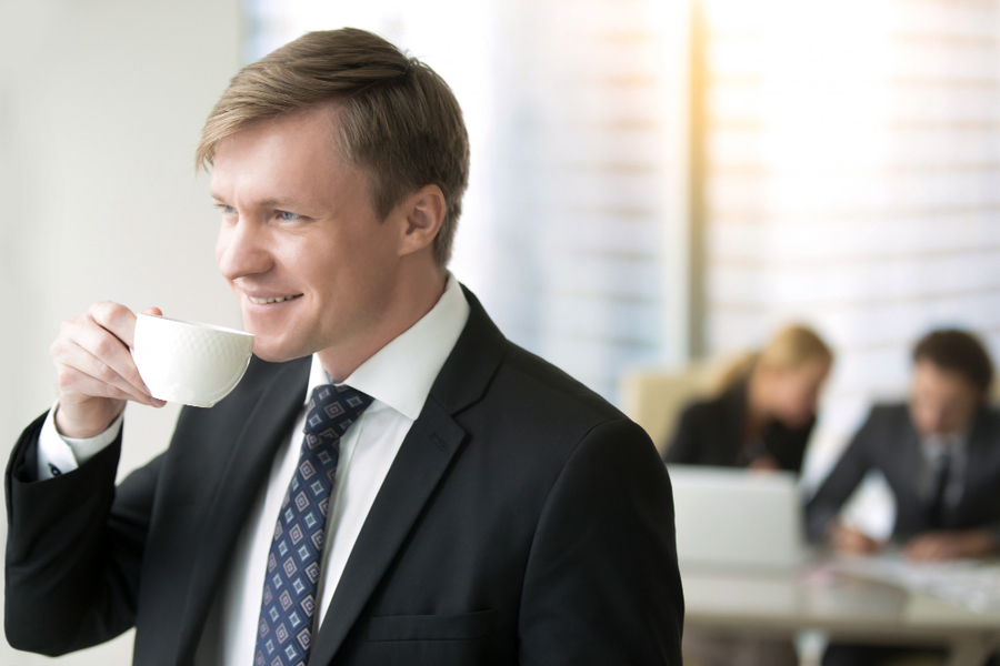 A smiling businessman holds a cup of coffee